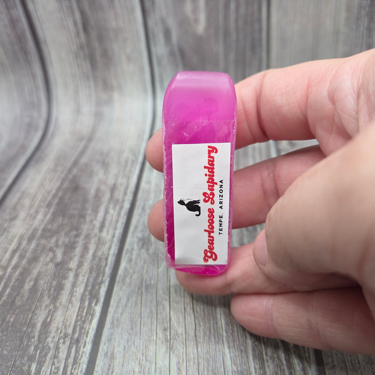 Hand holding the pink corundum Boule Tool™ with Gearloose Lapidary label